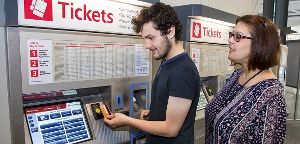 Woman helping young male use ticket machine